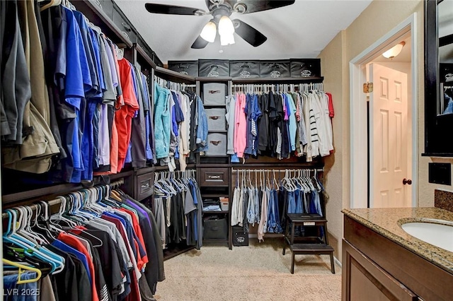 spacious closet featuring ceiling fan, light colored carpet, and a sink