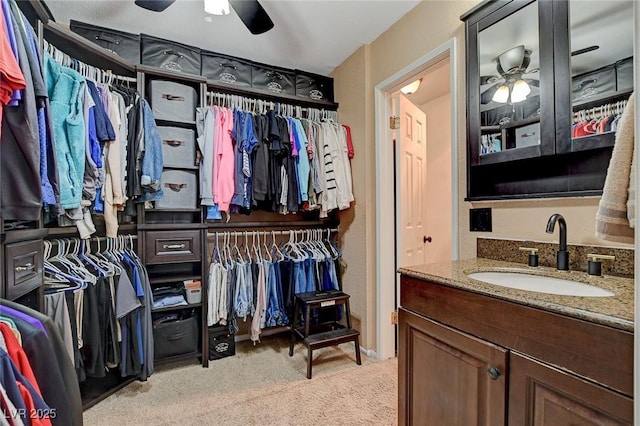 walk in closet featuring light carpet, a ceiling fan, and a sink