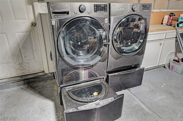 clothes washing area with washing machine and clothes dryer and cabinet space