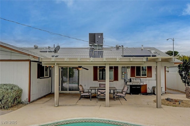 rear view of house with outdoor dining space, a patio, fence, central air condition unit, and roof mounted solar panels