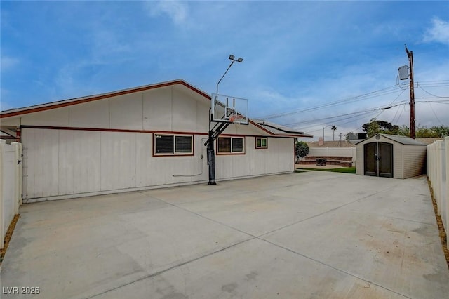 view of side of home with an outbuilding, a storage shed, and fence