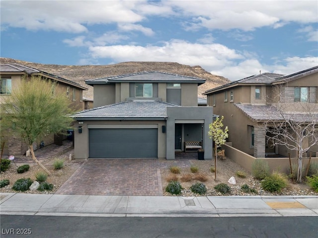 view of front of property featuring decorative driveway, a tile roof, a mountain view, and stucco siding