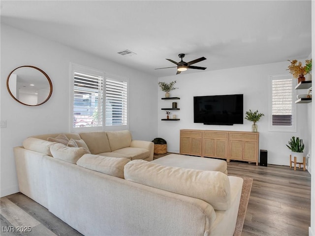 living room with a ceiling fan, wood finished floors, and visible vents