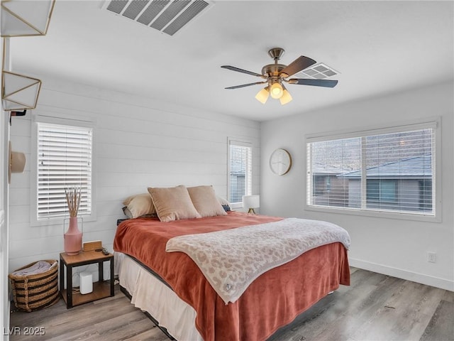 bedroom featuring a ceiling fan, wood finished floors, visible vents, and baseboards