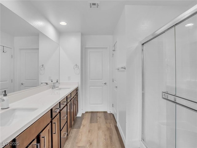 full bath featuring visible vents, a stall shower, wood finished floors, and a sink