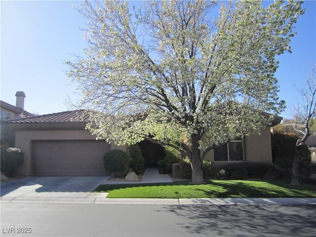 view of front of home featuring stucco siding, concrete driveway, a front yard, a garage, and a tiled roof