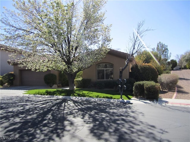 view of front of house featuring a tiled roof, concrete driveway, a front yard, stucco siding, and a garage