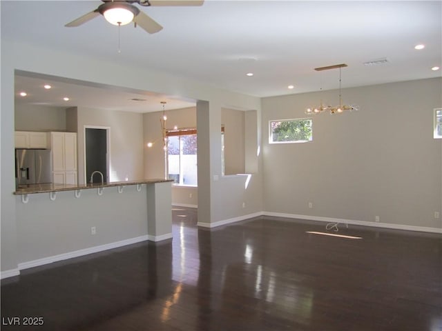 unfurnished living room with visible vents, a sink, dark wood finished floors, recessed lighting, and baseboards