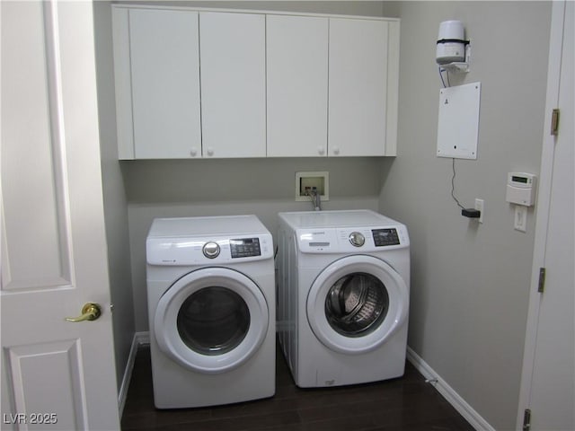 washroom featuring cabinet space, independent washer and dryer, dark wood-type flooring, and baseboards