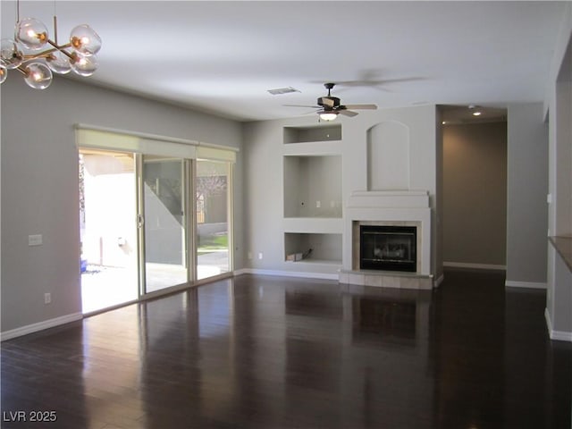 unfurnished living room with built in features, baseboards, dark wood finished floors, and a tile fireplace