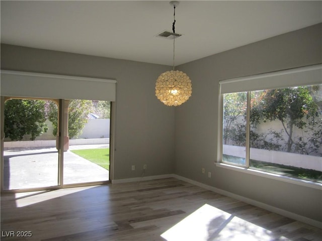 spare room featuring visible vents, baseboards, and wood finished floors