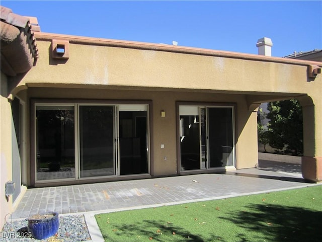 rear view of property featuring stucco siding and a patio