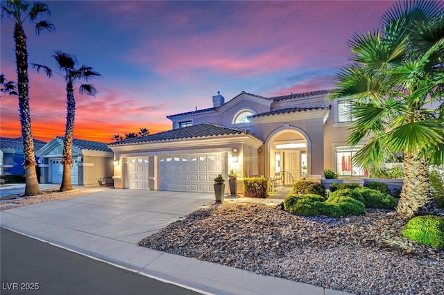 mediterranean / spanish house with stucco siding, driveway, a tile roof, and a garage