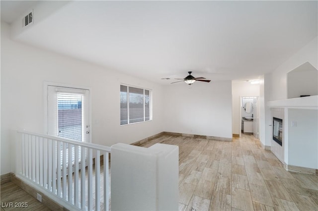 unfurnished living room featuring visible vents, ceiling fan, baseboards, a fireplace, and light wood-style floors