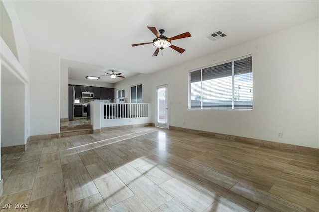 unfurnished living room featuring visible vents, baseboards, light wood-style floors, and a ceiling fan