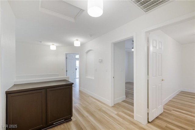 hallway with light wood finished floors, visible vents, and baseboards