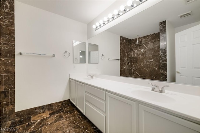 bathroom featuring visible vents, marble finish floor, a sink, double vanity, and walk in shower