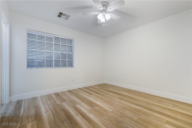 empty room featuring a ceiling fan, baseboards, visible vents, and light wood finished floors