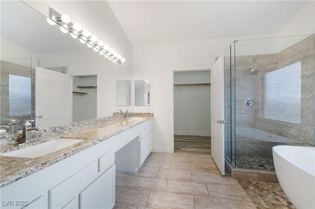 full bath with a stall shower, a sink, lofted ceiling, a soaking tub, and a spacious closet