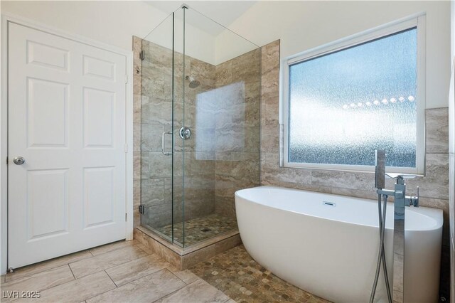 bathroom featuring a freestanding tub, tile walls, and a shower stall