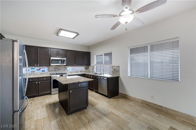 kitchen with a sink, backsplash, a center island, stainless steel appliances, and light stone countertops