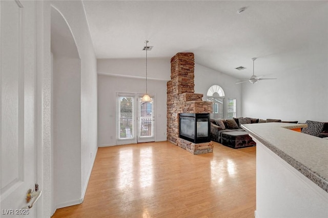 unfurnished living room featuring a stone fireplace, plenty of natural light, visible vents, and light wood finished floors