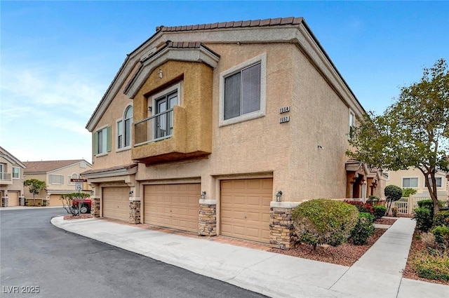 exterior space with stone siding, stucco siding, an attached garage, and fence