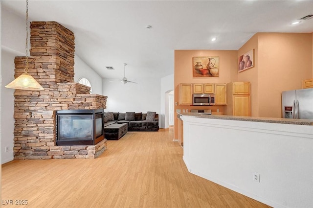 living room featuring a ceiling fan, light wood-style flooring, a fireplace, and visible vents