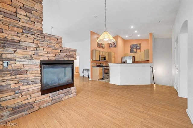 unfurnished living room featuring a stone fireplace, light wood-style flooring, and recessed lighting