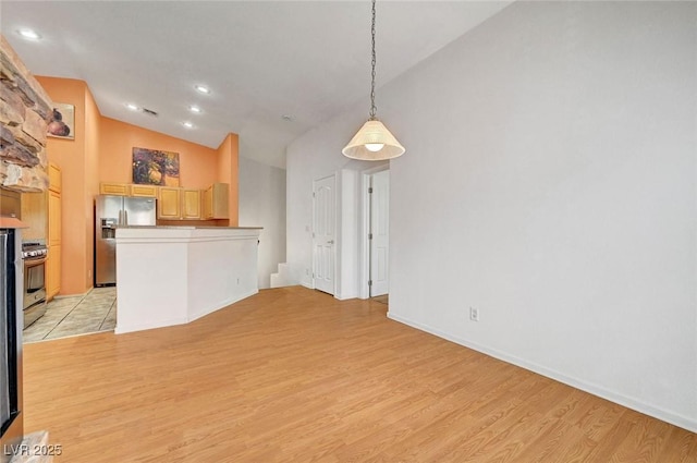 interior space with pendant lighting, light wood-style flooring, stainless steel appliances, a peninsula, and lofted ceiling