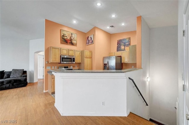 kitchen with light wood finished floors, light brown cabinets, recessed lighting, appliances with stainless steel finishes, and arched walkways