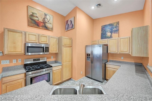 kitchen featuring visible vents, light brown cabinets, stainless steel appliances, and a sink