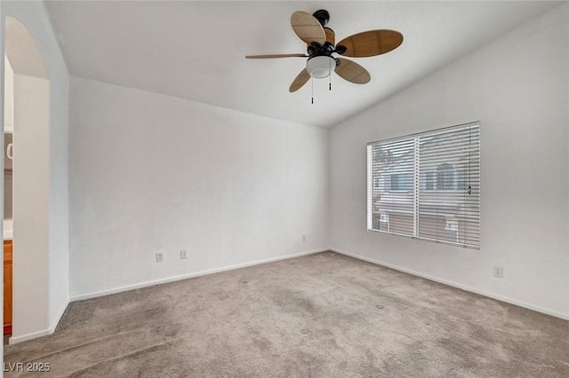 spare room with lofted ceiling, a ceiling fan, arched walkways, carpet, and baseboards