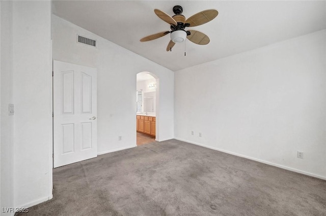 unfurnished bedroom with carpet, visible vents, baseboards, arched walkways, and connected bathroom