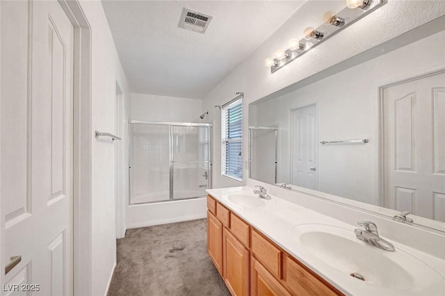 full bath featuring a sink, visible vents, shower / bath combination with glass door, and double vanity