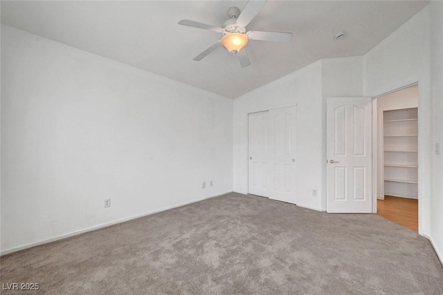 unfurnished bedroom with a closet, carpet floors, ceiling fan, and vaulted ceiling