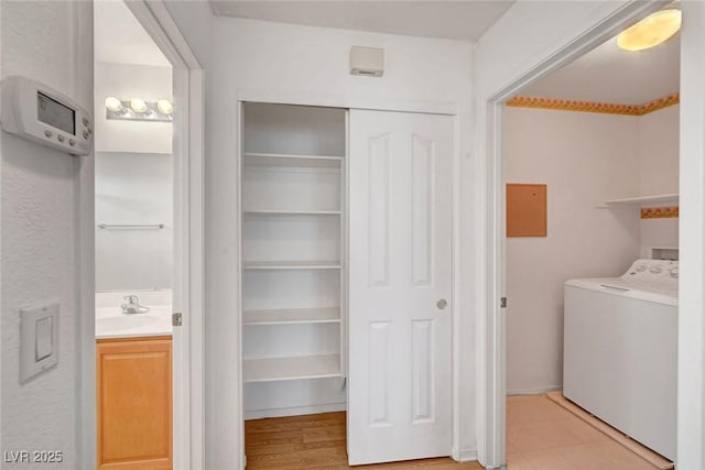 clothes washing area featuring laundry area, washer / clothes dryer, and a sink