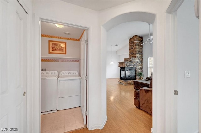 clothes washing area featuring washer and clothes dryer, laundry area, a fireplace, and light wood-type flooring