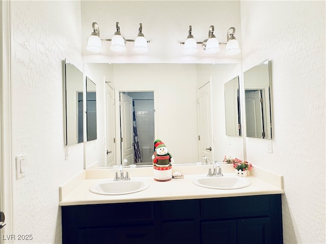 bathroom with a sink, double vanity, and a textured wall