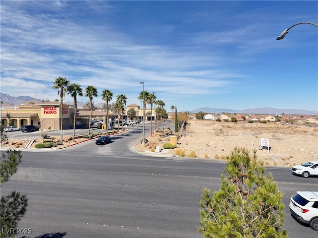 view of street featuring curbs, a mountain view, and street lights