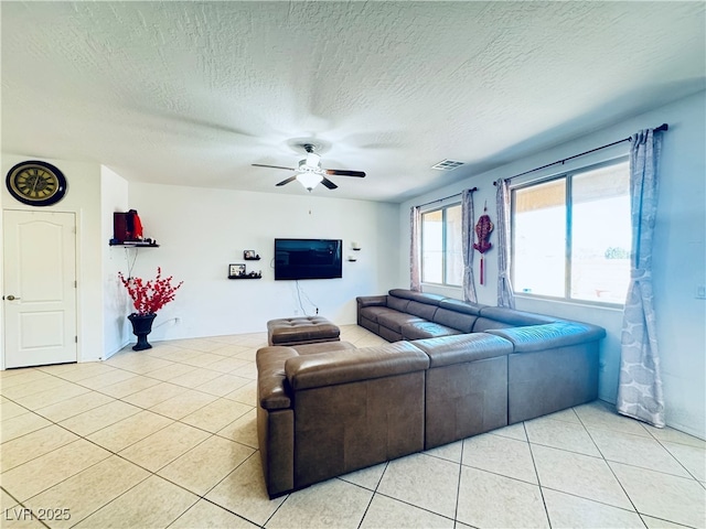 living room featuring light tile patterned floors, a ceiling fan, visible vents, and a textured ceiling