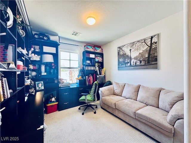 carpeted office space with visible vents and a textured ceiling