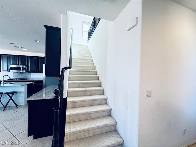 stairway featuring tile patterned floors and a textured ceiling