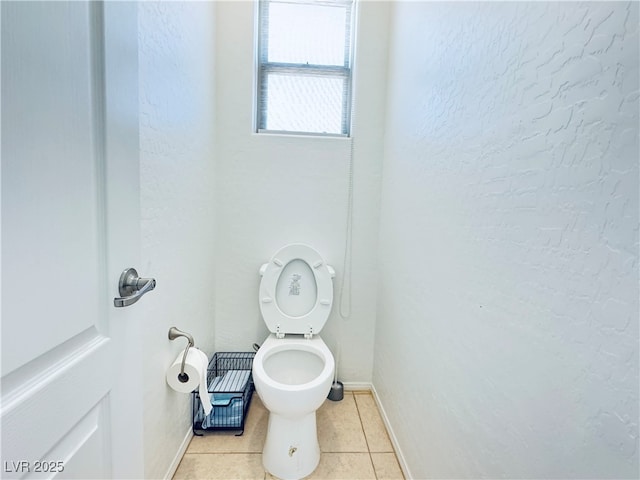 bathroom featuring tile patterned floors, baseboards, toilet, and a textured wall