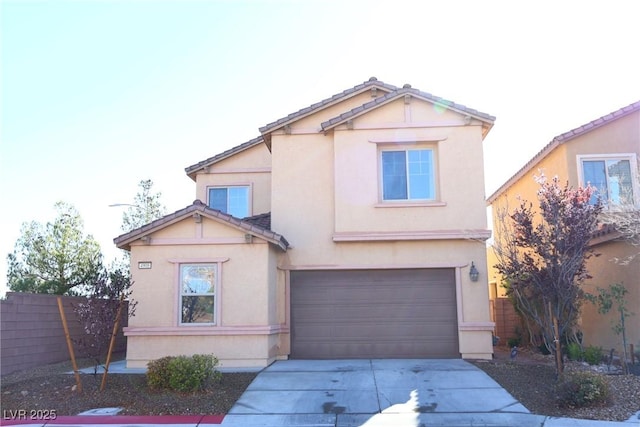 traditional-style house with fence, driveway, an attached garage, stucco siding, and a tiled roof