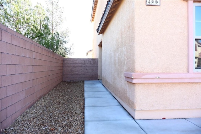 view of side of home featuring stucco siding and fence