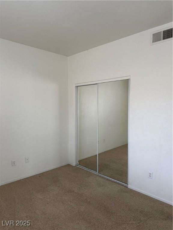 unfurnished bedroom featuring a closet, visible vents, and carpet flooring