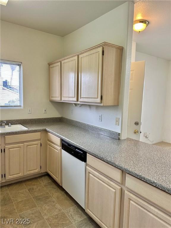 kitchen featuring light brown cabinets, white dishwasher, and a sink