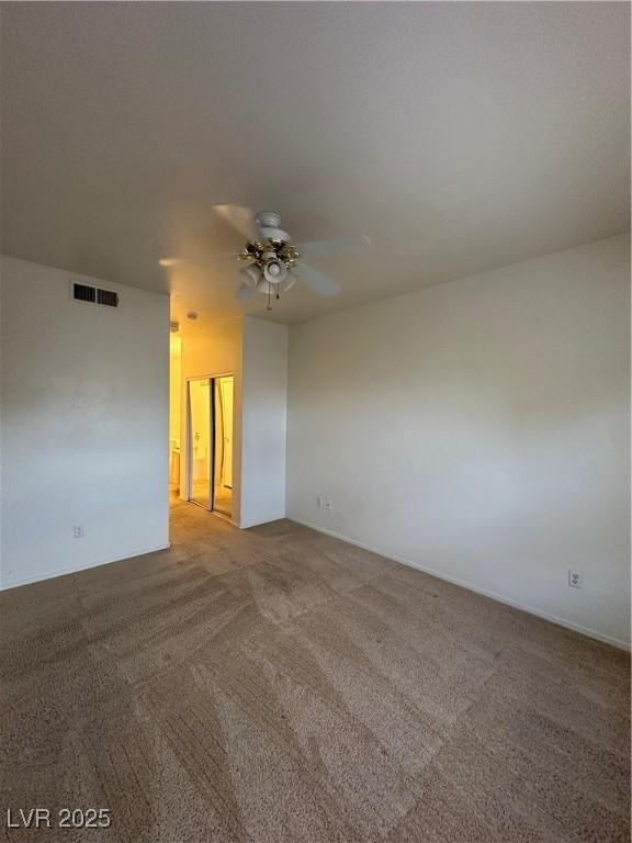 unfurnished room with visible vents, carpet, and ceiling fan