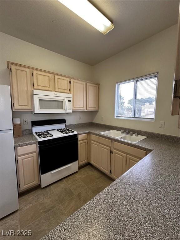 kitchen featuring white appliances, dark countertops, light brown cabinets, and a sink